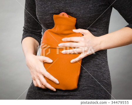 Girl having stomach ache, holding hot water bottle 34479555