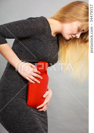 Girl having stomach ache, holding hot water bottle 34479557