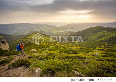 Photographer with backpack hiking in mountains. 34482270
