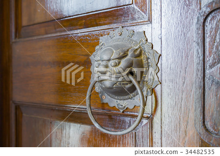 Brass lion head door knocker on wooden door 34482535