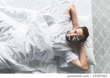 Attractive young man relaxing on bed Attractive young man relaxing on bed 34487463