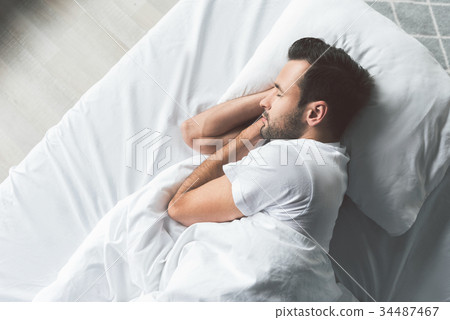 Cute young man sleeping on bed 34487467
