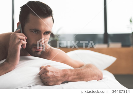 Pensive guy talking on mobile phone after sleeping Pensive guy talking on mobile phone after sleeping 34487514