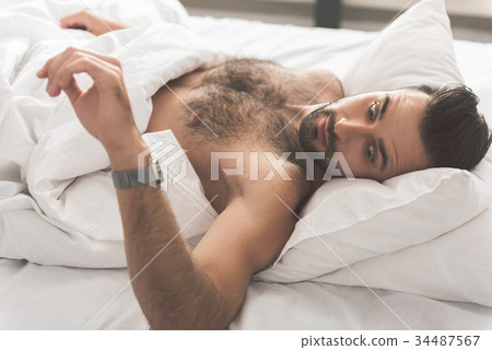 Surprised guy looking at watch in bedroom 34487567