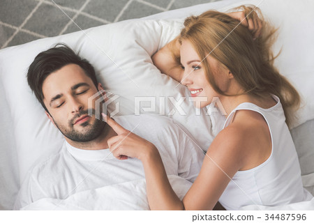 Cheerful couple relaxing on bed together 34487596