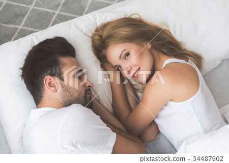 Cute young woman lying on bed near her husband 34487602