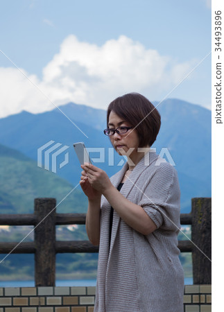 Middle woman operating smartphone in autumn tourist fall Middle woman operating smartphone in autumn tourist fall 34493896