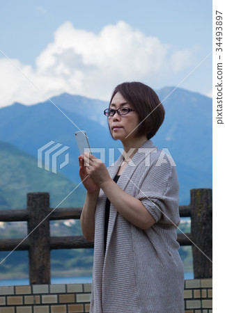 Middle woman operating smartphone in autumn tourist fall Middle woman operating smartphone in autumn tourist fall 34493897