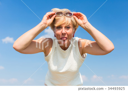 Funny senior woman sticking her tongue out while Funny senior woman sticking her tongue out while 34493925