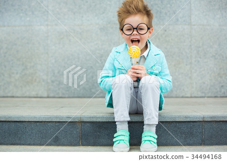 Fashion kid with lollipop near gray wall 34494168