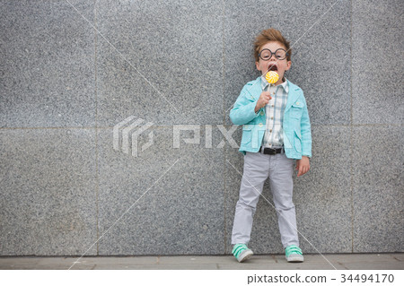 Fashion kid with lollipop near gray wall 34494170