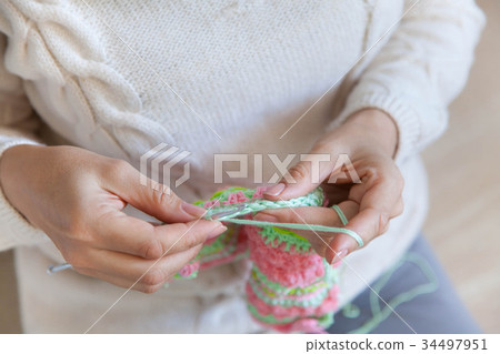 A woman knits a bright colored canvas with spokes 34497951