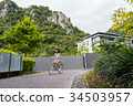 a short hair young woman is riding the bicycle 34503957