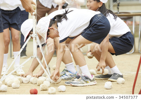 Elementary school students putting on ball at athletic meet 34507377