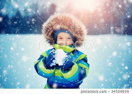 Boy in knitted hat, gloves and scarf outdoors at 34509939