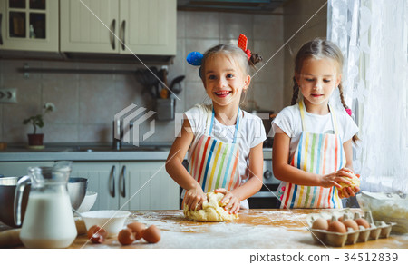 happy sisters children girls bake cookies, knead dough, play wit 34512839