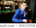 The groom in a blue suit is sitting in a bar with 34517058