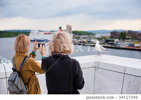 Two young stylish girls take pictures of a bird 34517349