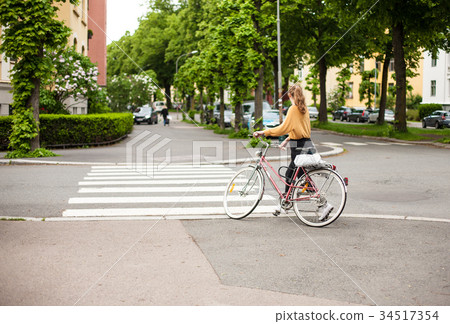 A girl with bicycle crosses the street in Oslo 34517354