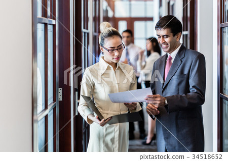 Executive and secretary standing in office hallway Executive and secretary standing in office hallway 34518652