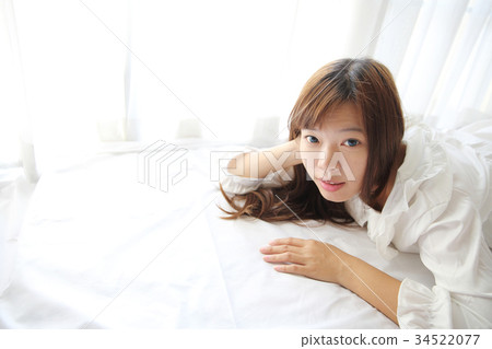 Asian young woman wake up with pillow in white room Asian young woman wake up with pillow in white room 34522077