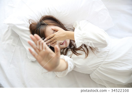 Asian young woman wake up with pillow in white room Asian young woman wake up with pillow in white room 34522108