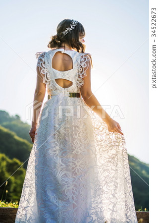 Bride in wedding dress facing the sunset 34522673