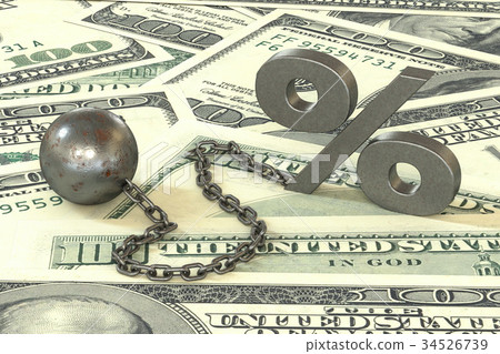 rust iron ball and chain with the cuff hanging percent symbol on dollars banknotes background.  34526739