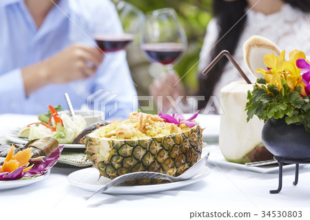 A couple is clinking wine glasses with several of Thai foods on the table. A couple is clinking wine glasses with several of Thai foods on the table. 34530803