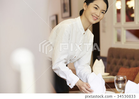 The staff of restaurant is putting the napkin on the table. 34530833