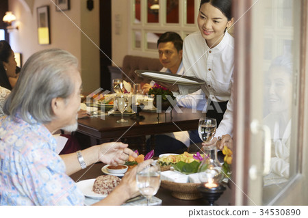 the waitress is serving water to a senior couple in a restaurant 34530890