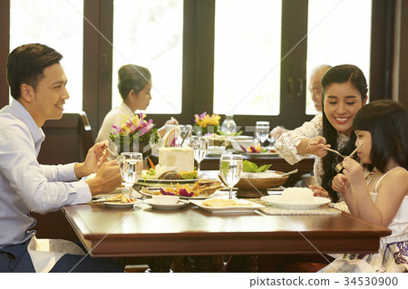 happy family with daughter having fun in a restaurant eating thai food 34530900