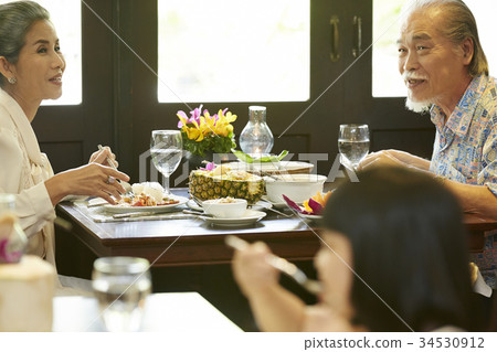 A senior couple is smiling while having a meal in a Thai restaurant. 34530912