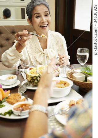 An older woman is smiling while enjoying Thai foods in a restaurant 34530928