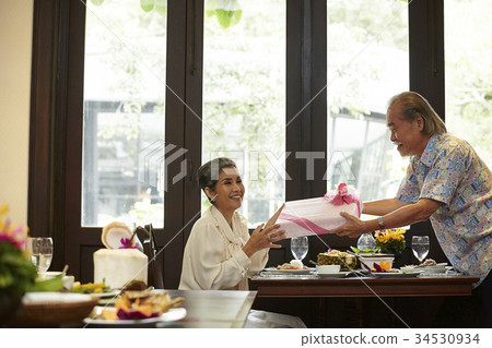 the woman is taking a gift box and smiling happily with her husband the woman is taking a gift box and smiling happily with her husband 34530934