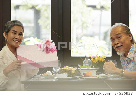 a happy senior couple is very happy with a gift pink box a happy senior couple is very happy with a gift pink box 34530938