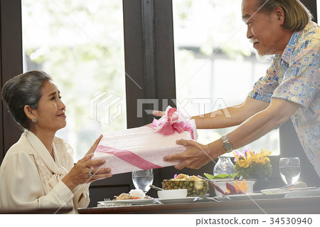 a senior man is smiling happily when giving a gift for his wife a senior man is smiling happily when giving a gift for his wife 34530940