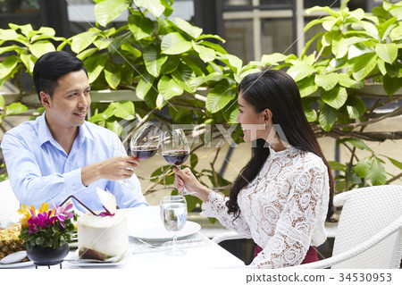 The happy couple is smiling while clinking wine glasses The happy couple is smiling while clinking wine glasses 34530953