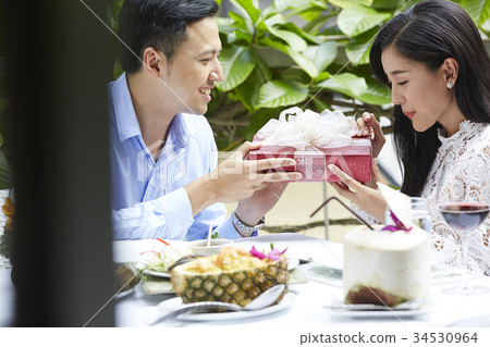 romantic boyfriend is giving a present to his girlfriend in restaurant 34530964