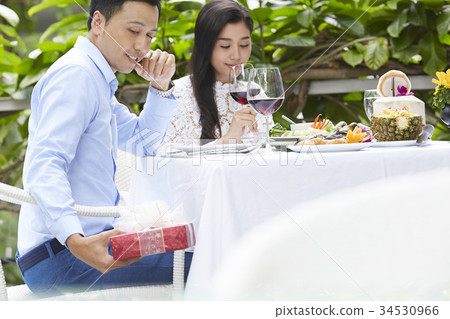 a man is preparing to give a surprised gift to his girlfriend in restaurant 34530966