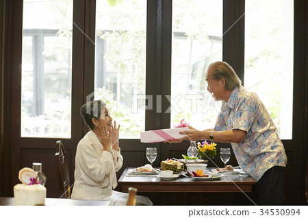 an old woman is surprised when seeing a present from her husband in restaurant an old woman is surprised when seeing a present from her husband in restaurant 34530994