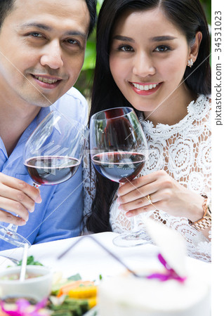 a happy young couple is holding glasses of red wine in a restaurant a happy young couple is holding glasses of red wine in a restaurant 34531023