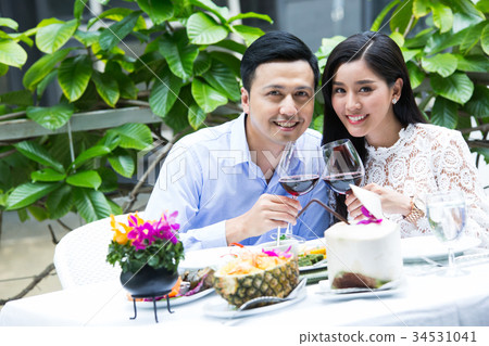 a young couple is clinking glasses of wine when having in lunch in a restaurant 34531041