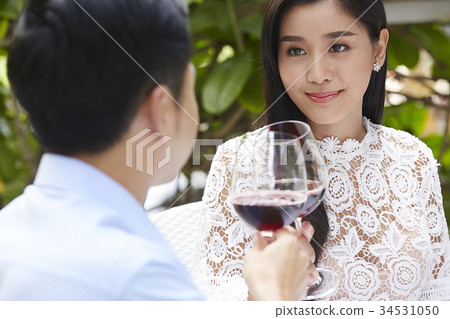a happy beautiful woman is clinking glasses of wine with her boyfriend a happy beautiful woman is clinking glasses of wine with her boyfriend 34531050
