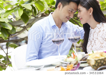 An Asian couple is leaning forehead to forehead at a meal. An Asian couple is leaning forehead to forehead at a meal. 34531064