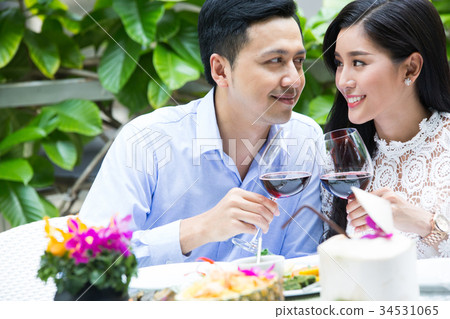 A couple is making a toast and looking at each other at a meal. 34531065