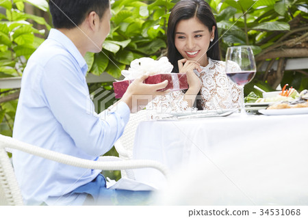 A young woman is feeling happy because of her boyfriend's gift at a restaurant. 34531068