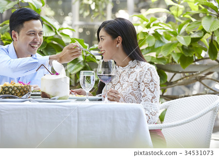 A man is giving his girfriend food at a restaurant. 34531073