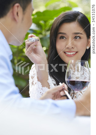 A woman is smiling and letting his boyfriend try eating her food. A woman is smiling and letting his boyfriend try eating her food. 34531076