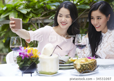 Two female friends are taking a sefie when having meal together. Two female friends are taking a sefie when having meal together. 34531097